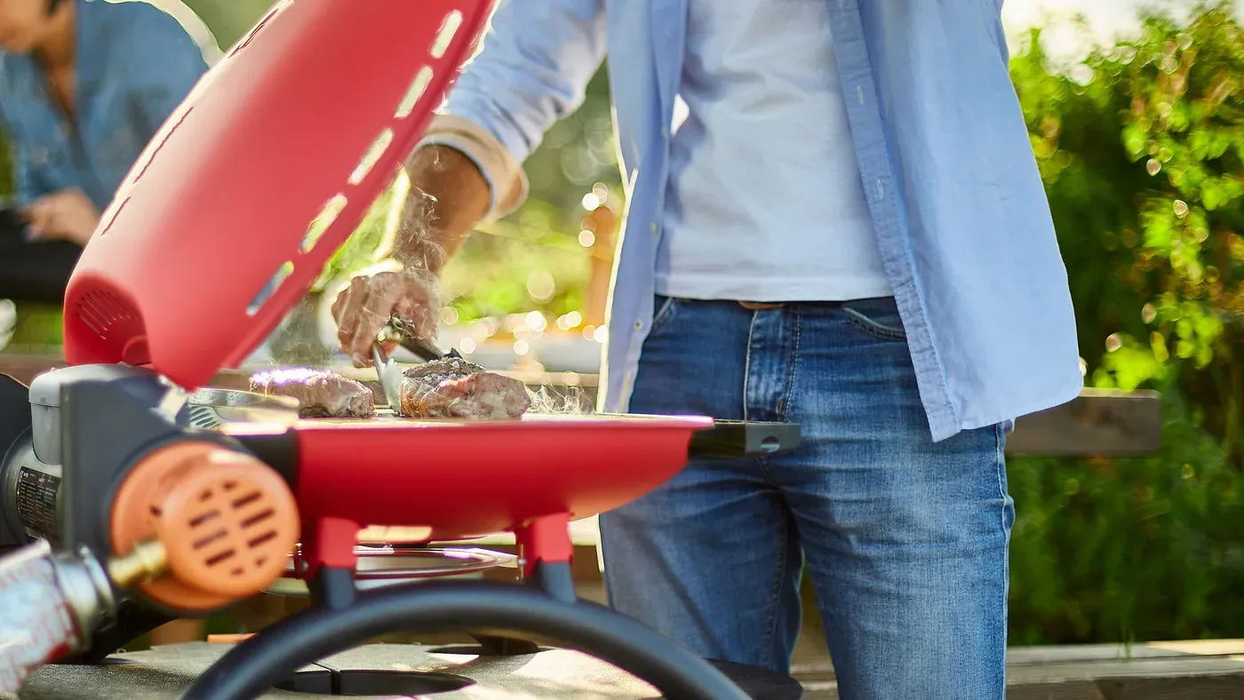 Gasolgrill med öppet lock på en uteplats